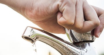 hand turning off water faucet