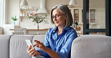 woman sitting on couch while scrolling on mobile phone