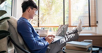 Young man feet up on desk looking at computer screen