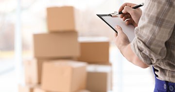 man with checklist and moving boxes in background