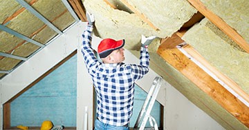man putting in insulation in attic